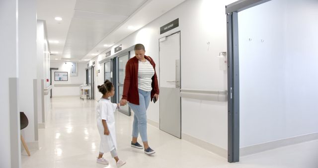Mother Holding Daughter's Hand while Walking in Hospital Hallway - Download Free Stock Images Pikwizard.com