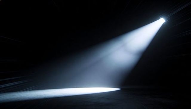 Dramatic White Spotlight Beam Casting Oval Patch on Dark Stage with Haze