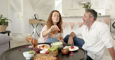 Mature Couple Cheers Over Wine and Snacks at Home