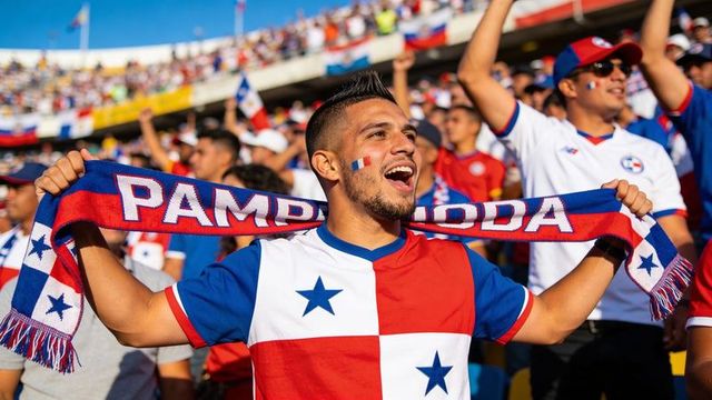 Passionate panama soccer fan cheering and holding scarf above head in crowded stadium