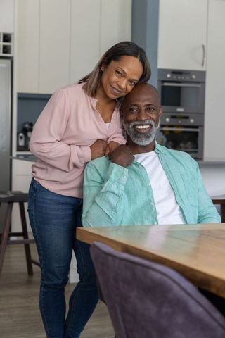 Smiling mature couple enjoying cozy kitchen moment, embracing warmth and togetherness