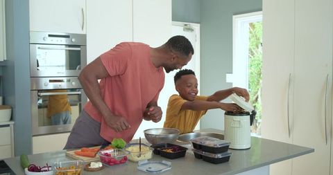 African american father and son prepping meals together in modern kitchen with rice cooker