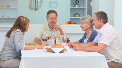 Friendly Gathering of Two Mature Couples at Dining Table