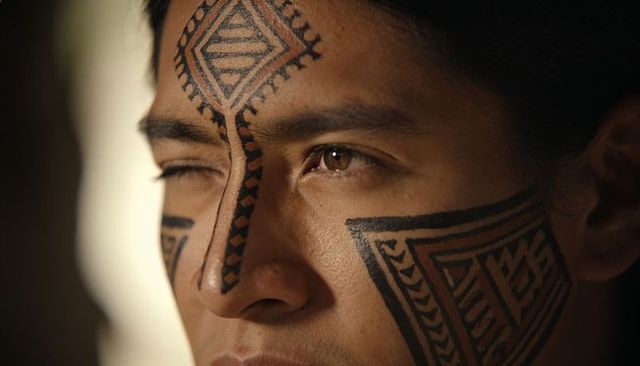 Closeup headshot man wearing geometric black facial tattoos in warm side lighting