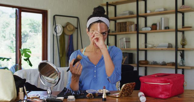 Portrait of biracial female vlogger applying make up at home. staying at home in self isolation in quarantine lockdown