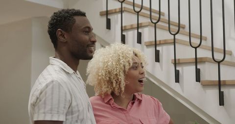 Joyful friends chatting at home by staircase