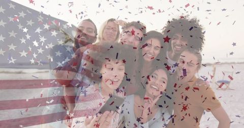 Diverse friends celebrating with american flag and confetti at beach
