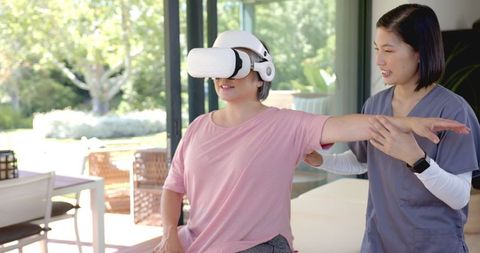 Senior woman using vr for physical therapy with therapist at home