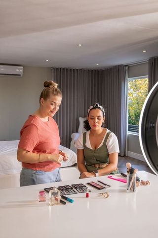 Diverse women sharing beauty tips in cozy home environment with makeup tools