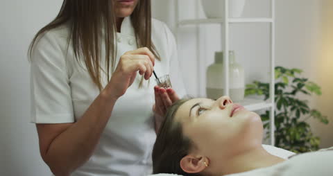 Beauty Technician Dying Eyebrows for Relaxed Client