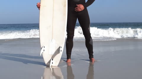Surfboard and Surfer on Beach Reflect Serenity and Adventure