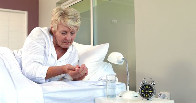 Senior woman taking pills on bed
