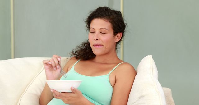Biracial pregnant woman eating at home, copy space. Pregnancy, motherhood, domestic life and wellbeing concept, unaltered.