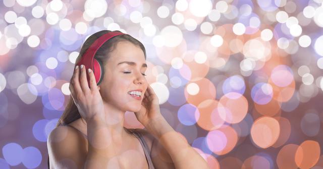 Young woman wearing headphones, singing with eyes closed, and enjoying music. Colorful bokeh background adds a festive and vibrant atmosphere. Perfect for use in music-related content, advertisements, entertainment promotions, or lifestyle blogs focusing on relaxation and enjoyment.