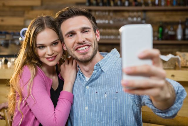 Young couple taking selfie on mobile phone in cafÃ©