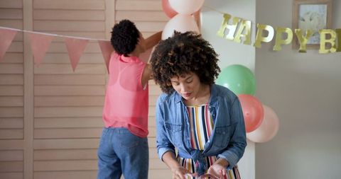 Women arranging balloons and banner for birthday celebration