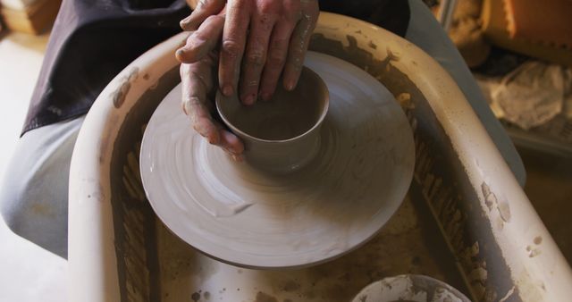 Close up view of male potter creating pottery on on potters wheel at pottery studio. hygiene and social distancing in the pottery studio during coronavirus covid 19 pandemic.