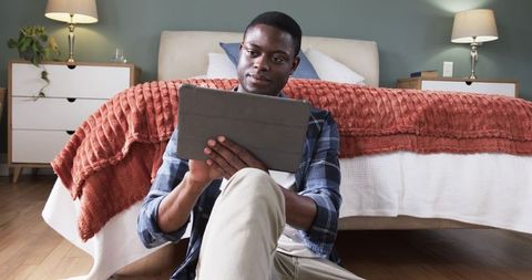 Man Using Tablet in Cozy Bedroom Retreat for Leisure