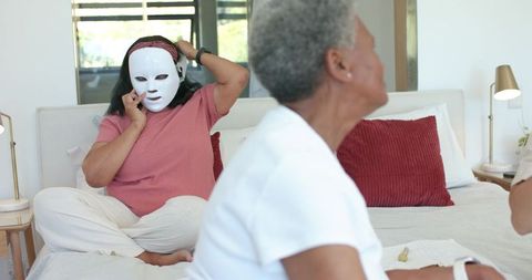 African american women using led facial mask at home spa bonding and skincare routine