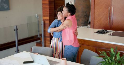 Lesbian Couple Celebrating Success with Documents at Home