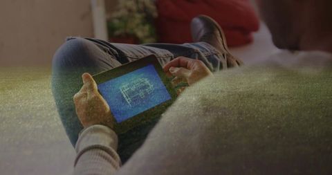 Man relaxing with tablet reviewing architectural blueprint at home
