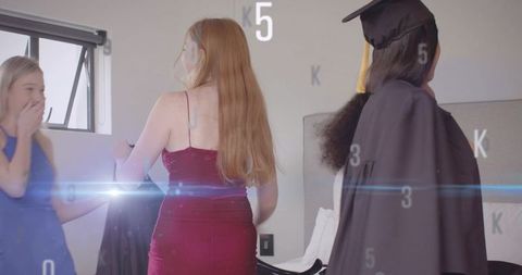 Friends Celebrating Graduation Eve Preparing Gowns and Cap in Casual Bedroom Moment