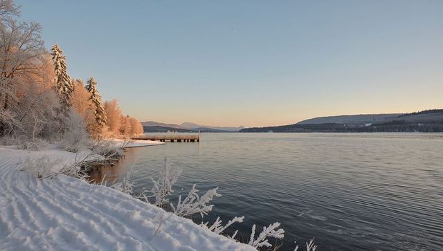 Sunrise Lighting Frosted Pines on Snowy Lakeshore with Wooden Pier and Rippling Water