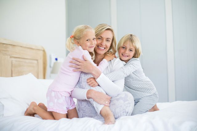 Portrait of smiling kids embracing her mother in bedroom at home
