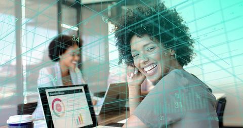 Smiling professional collaborating and analyzing data with tablet and teal grid overlay