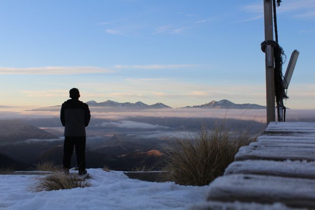 Man Standing on Snow-Covered Landscape Overlooking Mountains at Dawn - Download Free Stock Photos Pikwizard.com