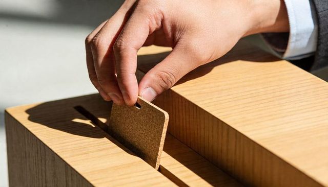 Placing cork tag into wooden slot by suited hand closeup for vote suggestion concept