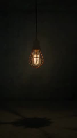 Caged Edison Bulb Swinging on Cord Casting Shifting Shadows — Vertical Cinematic Loop