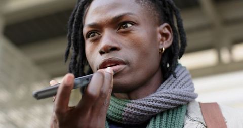 African american commuter speaking into smartphone on transit platform urban portrait