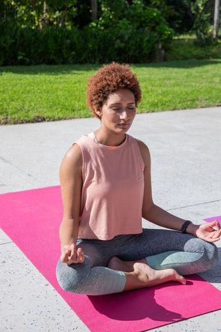 African American Woman Meditating Outdoors on Pink Yoga Mat