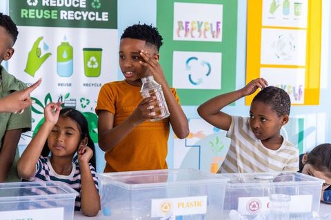 Children sorting plastic recycling in classroom, learning sustainability and teamwork