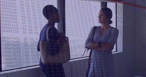 Businesswomen discussing data strategy by office window with digital hex overlay