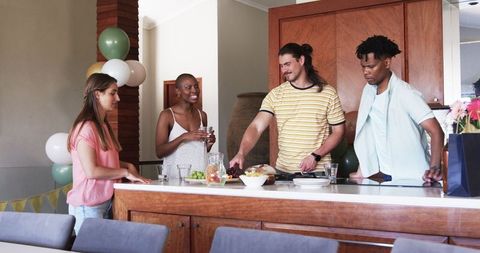 Friends Socializing and Cooking Food Together in Modern Kitchen