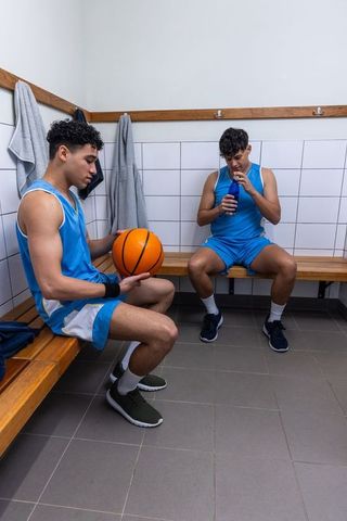 Basketball Players Relaxing in Locker Room Holding Basketball