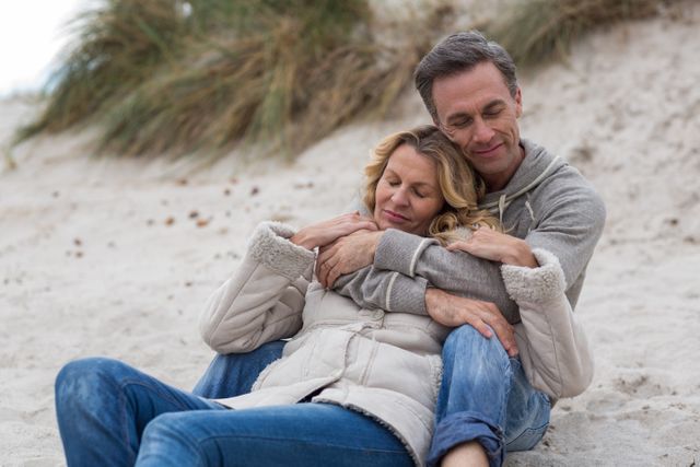 Mature couple enjoying a tender moment on a sandy beach. Ideal for use in advertisements, greeting cards, relationship advice blogs, or retirement lifestyle promotions, highlighting love, romance, and togetherness.