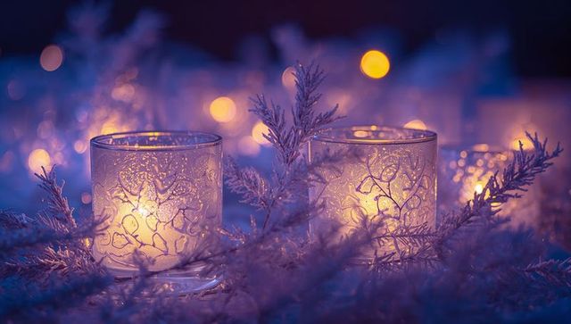 Glowing etched glass votives casting warm candlelight through frosted branches