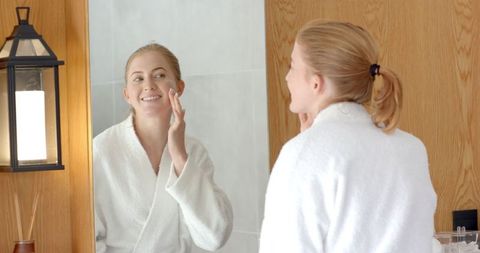 Woman Applying Skincare Product at Modern Bathroom Vanity