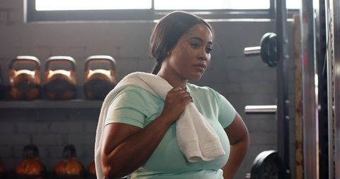 African american woman resting with towel at gym showing determination and focus