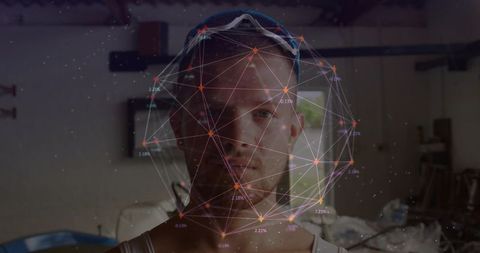 Man wearing tank top viewing augmented reality network sphere in garage workshop