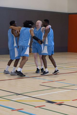 Diverse Male Basketball Team Celebrating Victory on Court