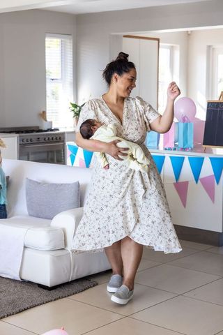 Joyful mother celebrating with newborn in bright family home