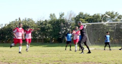 Amateur soccer players defending goal with goalkeeper directing defense