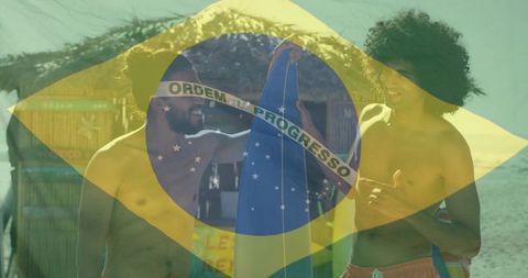Holding brazilian flag and surfboard, surfers celebrating on tropical beach
