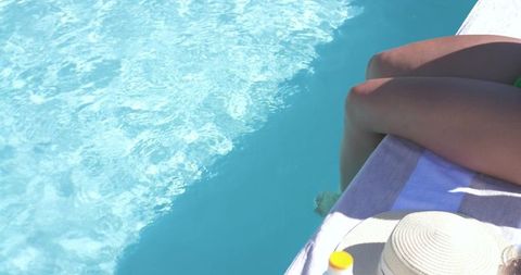 African american woman lounging poolside with sunhat and sunscreen by turquoise water