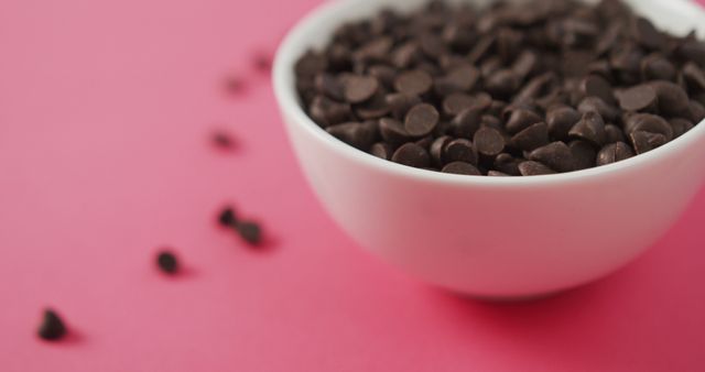 Image of close up of bowl of chocolate chip over pink background. fusion food, chocolate and sweets concept.
