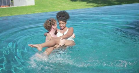 Couple enjoying romantic pool moment man carrying woman in turquoise infinity pool